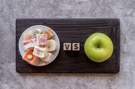 Healthy diet. Choosing between sweets and apple top view on dark background