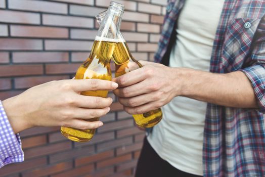 Friends enjoying with beer on a brown brick wall background.