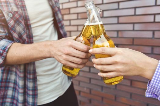 Friends enjoying with beer on a brown brick wall background.