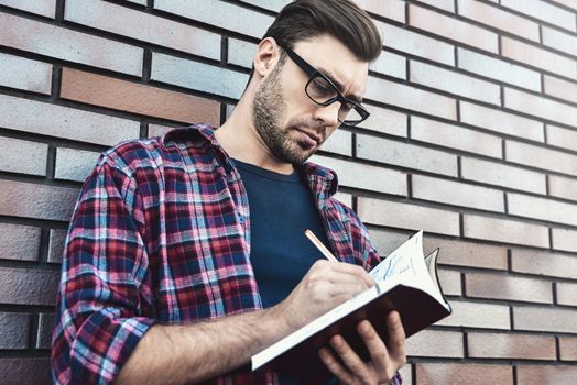 Portrait of handsome man in glasses and shirt isolated on brown brick wall.