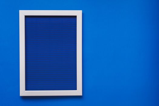 Empty  white frame on blue pattern texture of crumpled paper in the volume of horizontal lines hanging on blue wall.  Frame Concept. Flat lay. Blank Space