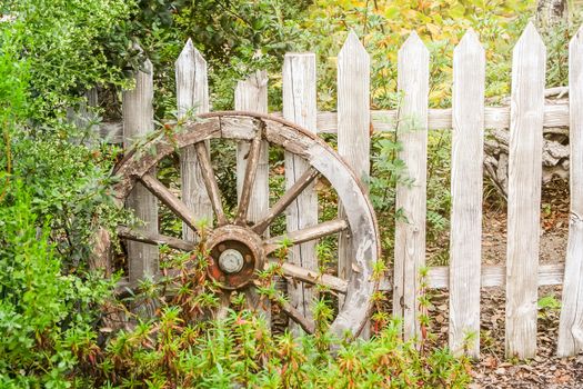 An image of a wooden wheel at a wooden fence