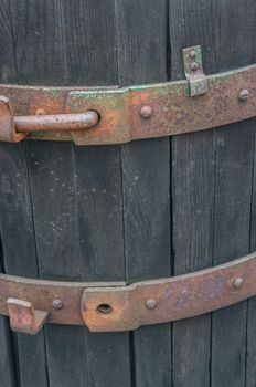 Closeup of rusted brass details with peeling green paint on a vintage rustic wine casket. Dark cold brown wooden barrel shot in daylight during winter season.