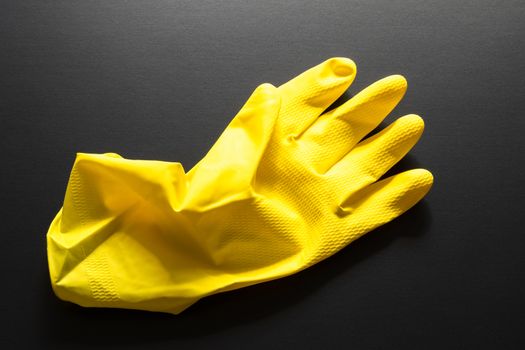 An image of a yellow rubber glove isolated on black background
