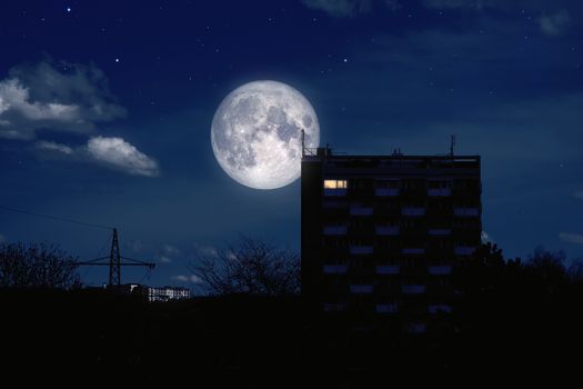 An image of a full moon over a modern building
