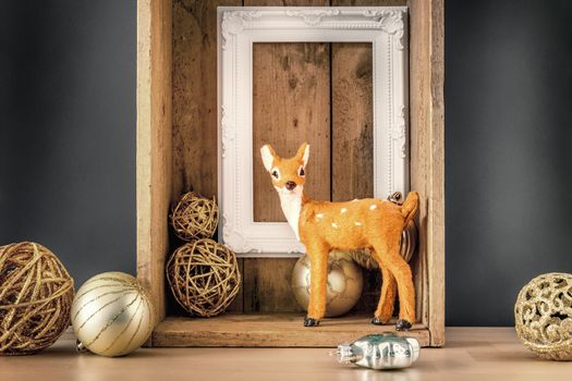 An image of a Christmas decoration wooden box with deer golden balls and a white frame