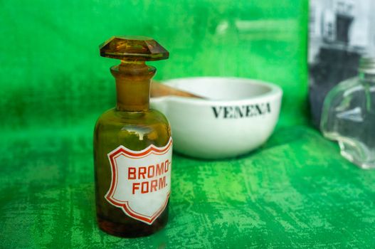 Vintage victorian glass medicine bottles and jars in a chemist display in macro on deep green background