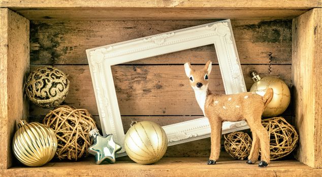 An image of a Christmas decoration wooden box with deer golden balls and a white frame