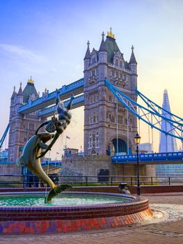 London, United Kingdom - April 17, 2019 : View of Tower Bridge on the River Thames with the Girl with Dolphin fountain, created by David Wynne in 1973.