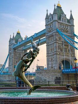 London, United Kingdom - April 17, 2019 : View of Tower Bridge on the River Thames with the Girl with Dolphin fountain, created by David Wynne in 1973.