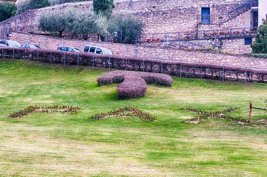Scenic garden with the symbol of Tau and the word Pax (Translation: "Peace") written in the grass, outside the Basilica of Saint Francis of Assisi, Italy
