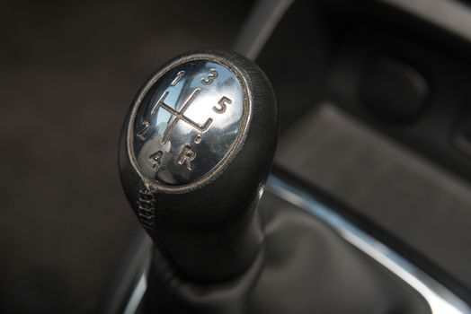 Interior of a car with closeup of a chromed gear shift for a 5-speed manual transmission gearbox