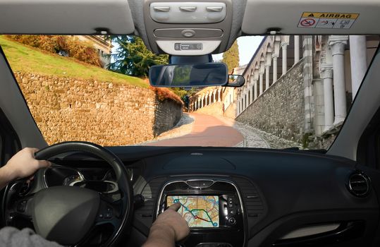 Driving a car while using the touch screen of a GPS navigation system on the slope to the Udine Castle, historical landmark in Udine, Italy