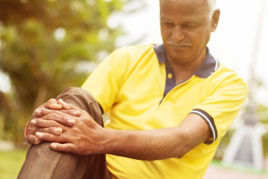 Elderly man having a knee injury - Concept Senior Man fitness and yoga at outdoor - Selective focucs on hand, old man holding knee due to pain