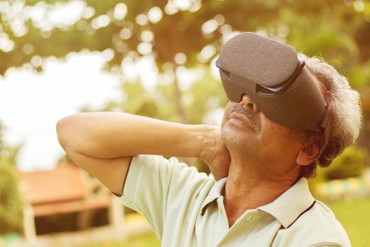 Senior man using VR google glass for exercise, Outdoor - Fitness concept using New technologies by elderly people - Old men stretching hands by watching Virtual Reality Goggles