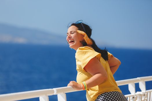 Happy Woman On A Cruise Vacation. standing on deck of cruise ship, strong wind blowing her hair