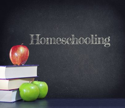 Homeschooling written on a vintage blackboard with apples and books.