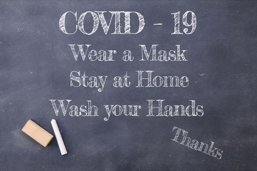 Coronavirus pandemic behaviour rules or health advice. Covid-19 wear a mask, Stay at Home and wash your hands chalkboard inscription.