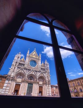 Siena, Italy - July 4, 2018: Siena Cathedral (Duomo di Siena) is a medieval church, now dedicated to the Assumption of Mary, completed between 1215 and 1263, Siena, Italy. View through a window