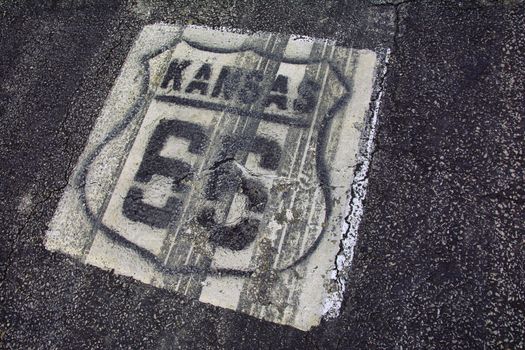 Historic Route 66 marker in Kansas on asphalt.