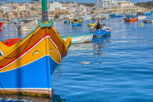 Marsaxlokk, Malta - January 10, 2020: Beautiful view of the traditional eyed colorful boats Luzzu in the Harbor of Mediterranean fishing village Marsaxlokk, Malta