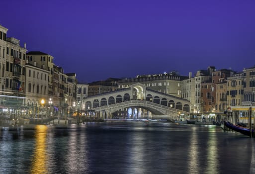 Venice, Italy - October 12, 2019: View of the Rialto Bridge and Grand Canal in a blue hour at sunset. Venice. Italy.