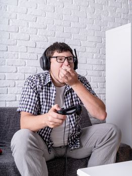 Stay home. Overeating. Unhealthy food. Young man playing video games at home eating popcorn