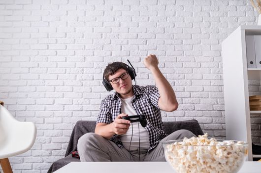 Stay home. Excited young man playing video games at home enjoying his victory