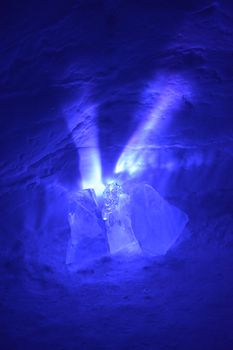 A small light source causes exploding purple rays to spread out from behind these chunks of ice. Reflections sparkle from the surrounding ice and snow. Portrait.