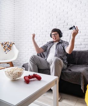 Stay home. Excited young man playing video games at home enjoying his victory