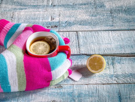 Female hands holding a cup of hot drink on rustic wooden table, close-up