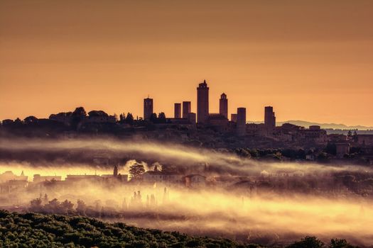 Beautiful sunset with fog at San Gimignano medieval village, Italy.