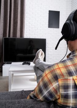 Stay home. Rear view of a young man playing video games at home