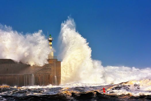 Stormy wave over lighthouse and pier of San Esteban de Pravia in Asturias, Spain.