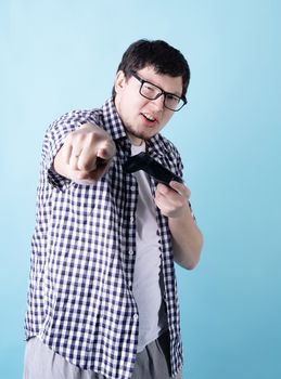 Stay home. Funny young man playing video games holding a joystick isolated on blue background