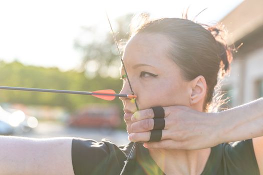 attractive sports woman in archery, arrows and bow in action.
