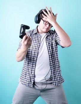 Stay home. Disappointed young man playing video games holding a joystick isolated on blue background