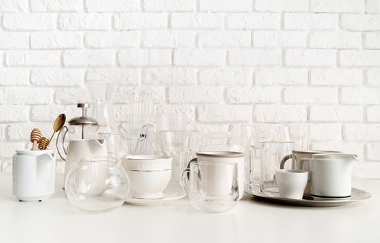 glass and ceramic cups, glasses, glassware for tea front view on the table on white brick wall background