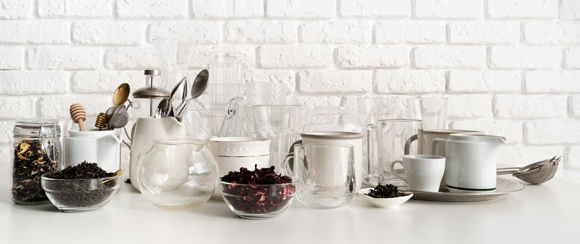 glass and ceramic cups, glasses, glassware for tea front view on the table on white brick wall background