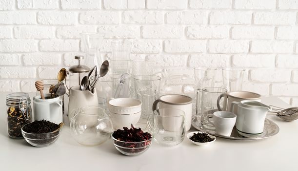 glass and ceramic cups, glasses, glassware for tea front view on the table on white brick wall background