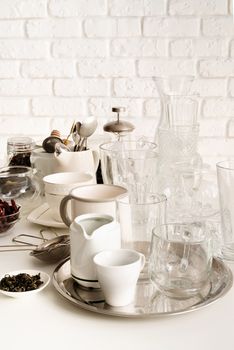 glass and ceramic cups, glasses, glassware for tea on the table on white brick wall background