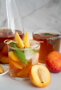 Jug with iced cold peach tea with fruit slices and mint