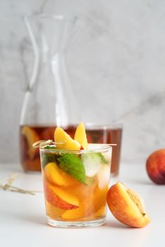 Glass of iced cold peach tea with fruit slices and mint