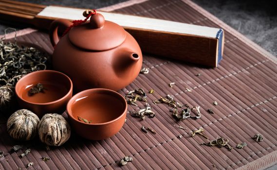 Asian teapot with cups and green tea on wooden placemat with copy space