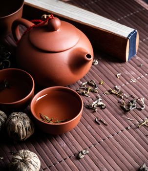 Asian teapot with cups and green tea on wooden placemat with copy space