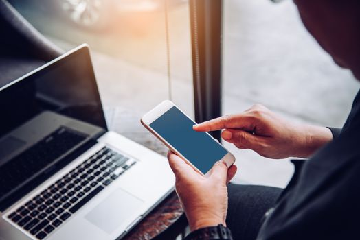 Businessmen use smartphones and laptop to connect and find information in office