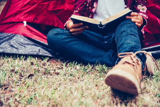 Teenagers are relaxing by reading books in tent picnic area in the garden.