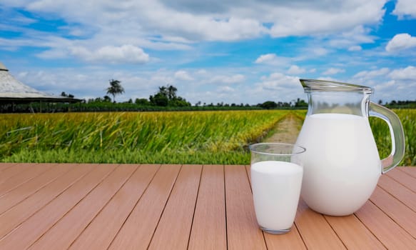 Fresh milk in clear glass and clear pitcher on lath floor With a rice field background With golden yellow rice, bright sky, white clouds .3D Rendering