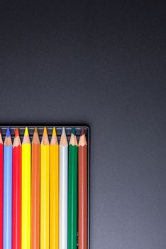 Color Pencils with plastic case isolated on Black Background close up. Colored style view top flat lay with free copy space for design or text. Back to school theme