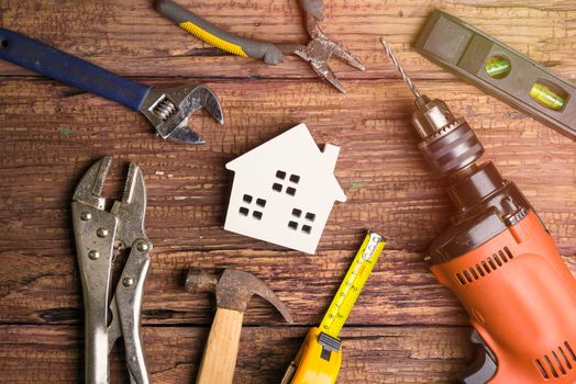 Wooden white house toy and construction tools on wooden background with copy space.Real estate concept, New house concept, Finance loan business concept, Repair maintenance concept